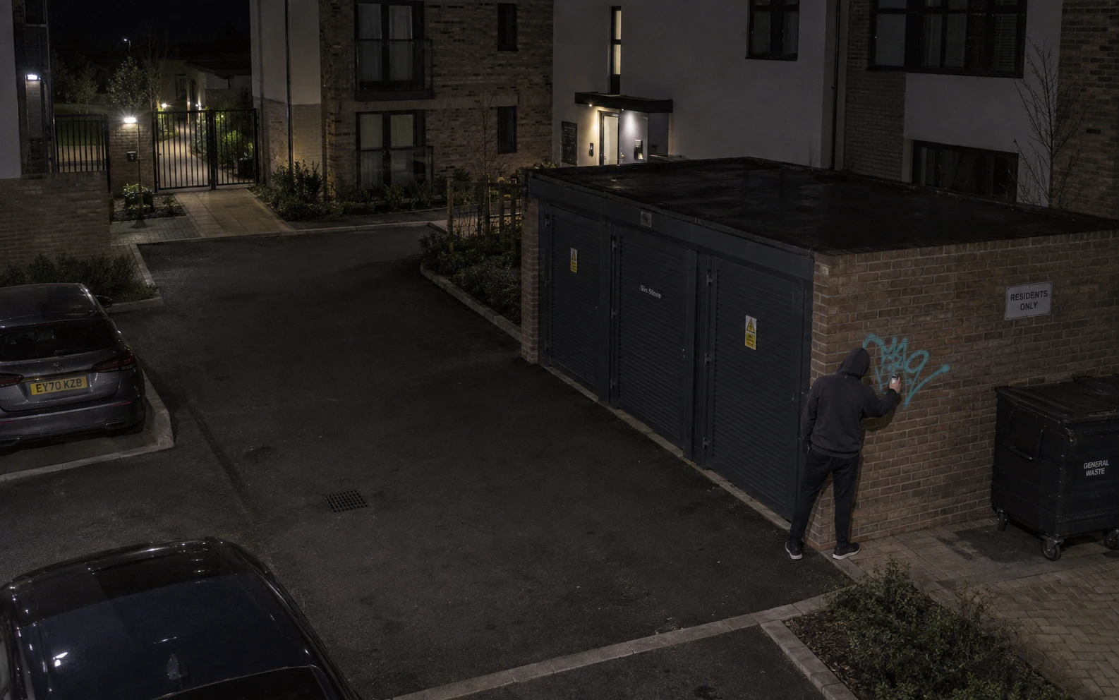 A person marking a wall on a managed property at night.