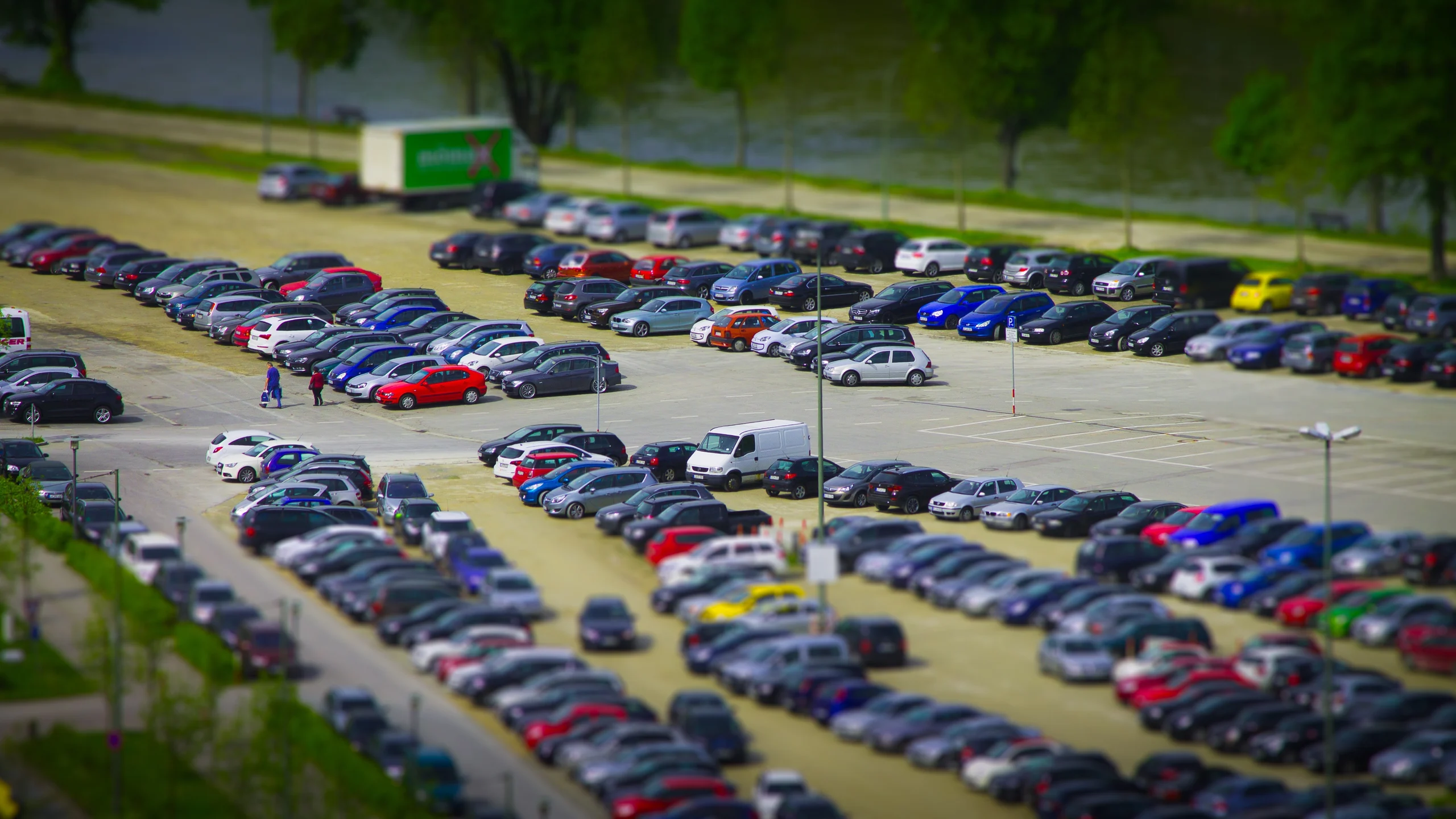 Elevated view across rows of parked cars and the access lanes of a busy car park.