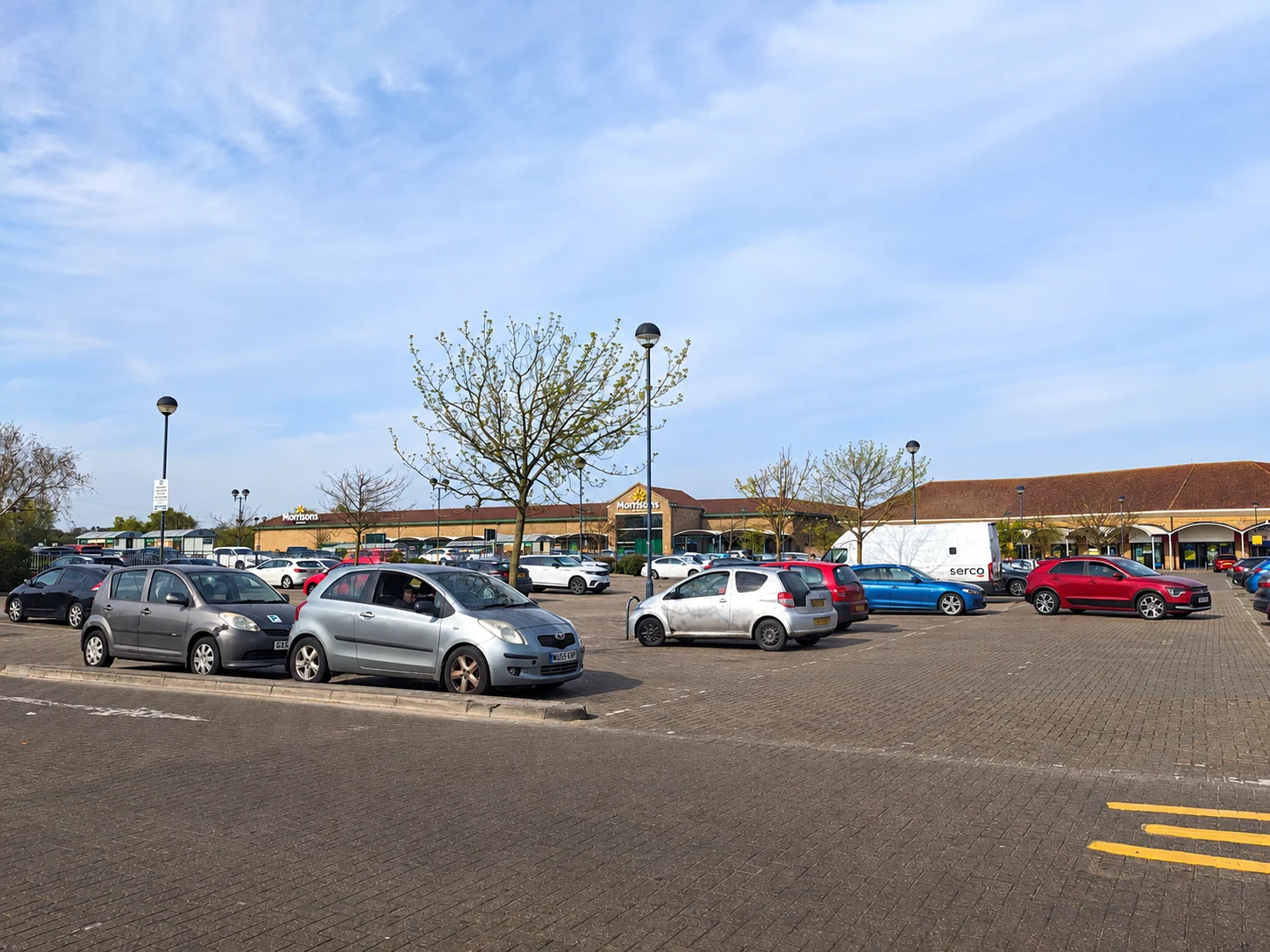 Cars at the entrance and access road of a supermarket car park.