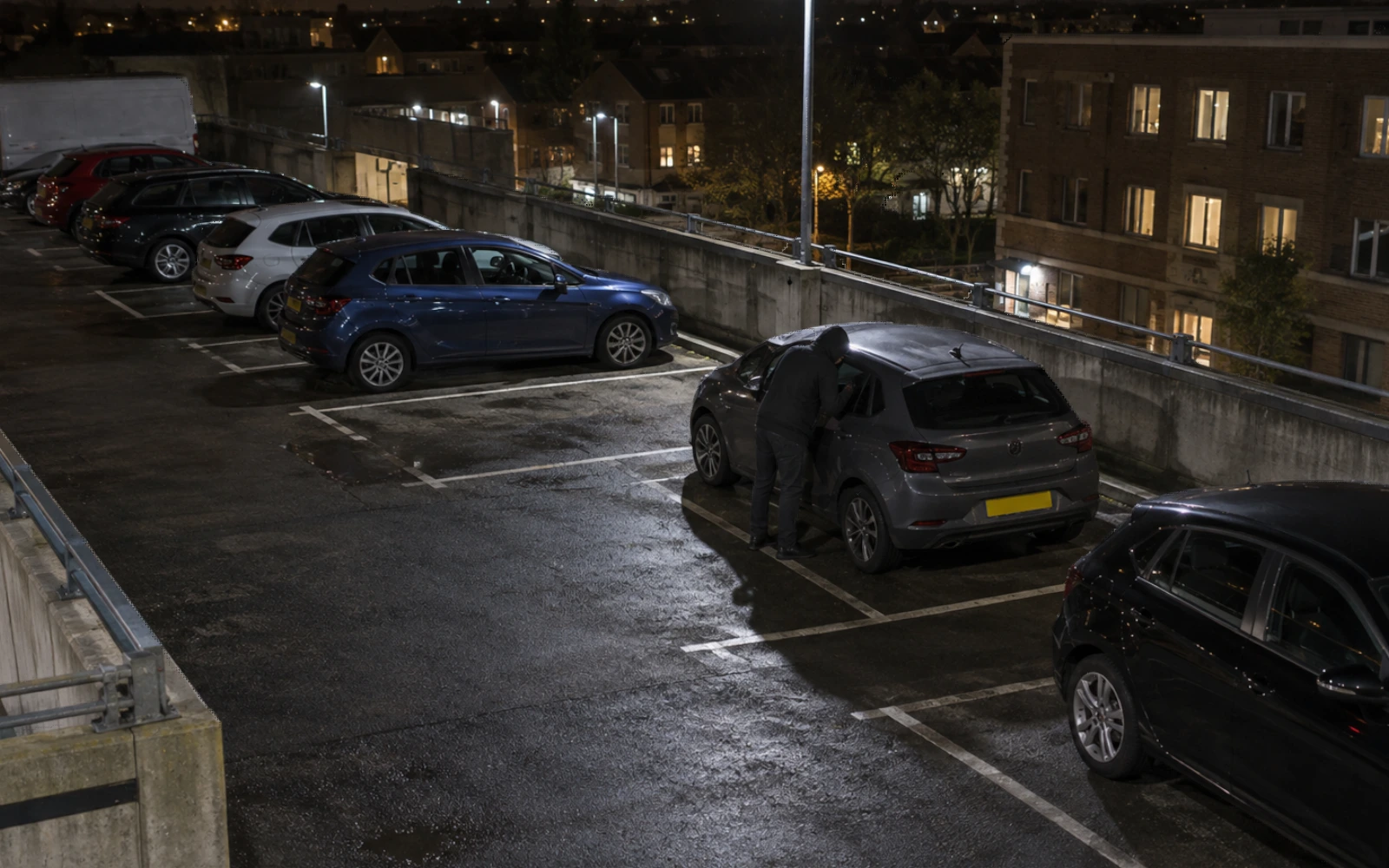 Elevated camera view of activity beside a parked vehicle.