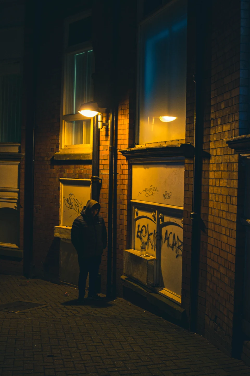 Graffiti on an exterior doorway and brick wall at night.