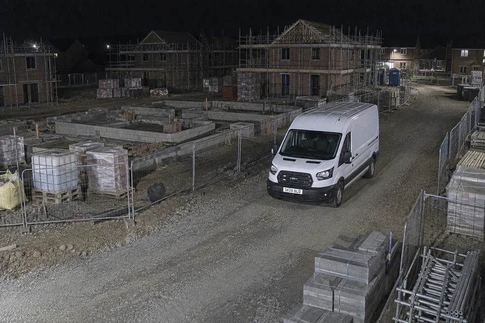 A white van on a housing construction site captured in colour at night.