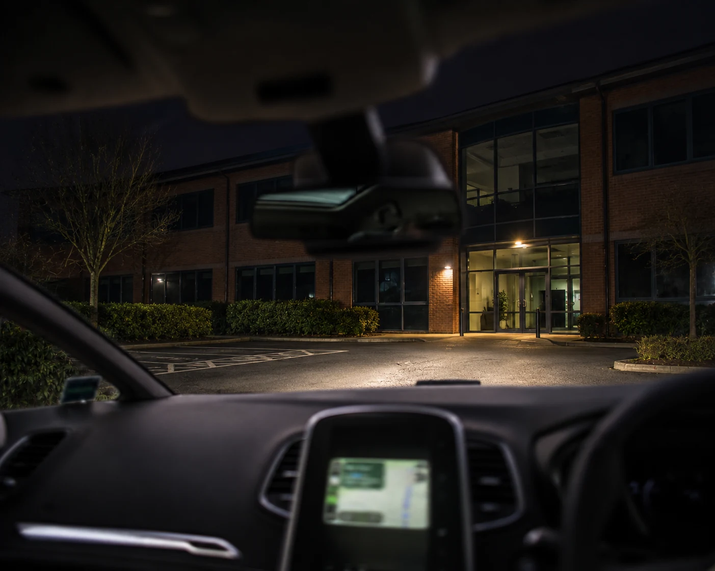 View from a patrol vehicle approaching an office building at night.