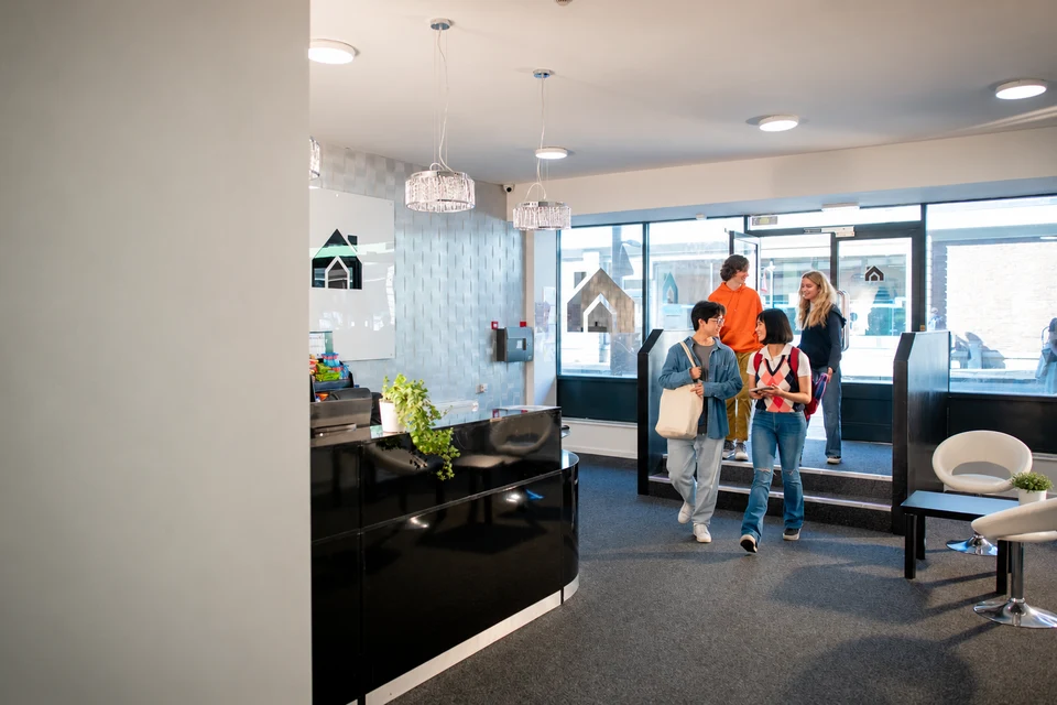 Four students arriving through the entrance of their accommodation.